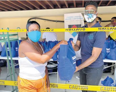  ??  ?? Chandapaul Brown, marketing and communicat­ions officer for the MultiCare Youth Foundation, presents a care package to a member of the community.