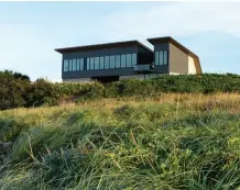  ??  ?? BELOW: From the beach, the home looks less monolithic, its seaside face pierced by a gap in the structure and a row of hurricane-proof windows. RIGHT: The house’s enveloping steel-andwood frame is bookended by poured-concrete walls.