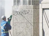  ?? BRANDON HARDER ?? A worker power washes the graffiti off the memorial.