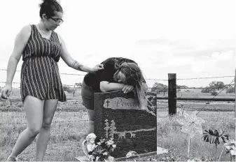  ??  ?? Marina Pomeroy comforts her mother, Sherri, as they visit the grave of her sister Annabelle, who had turned 14 a couple of weeks before the shooting.