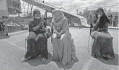  ??  ?? Nur Syamim Ah, left, and her friends, who did not want to be identified, watch the merry-go-round at the Eid al-Fitr Festival.