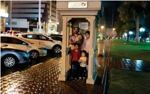  ?? Photo by Sajjad ?? HELTER SHELTER: A family takes cover inside a phone booth in Sharjah. —