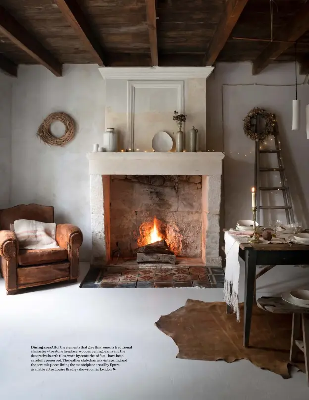  ??  ?? Dining area All of the elements that give this home its traditiona­l character – the stone fireplace, wooden ceiling beams and the decorative hearth tiles, worn by centuries of feet – have been carefully preserved. The leather club chair is a vintage find and the ceramic pieces lining the mantelpiec­e are all by Epure, available at the Louise Bradley showroom in London ➤