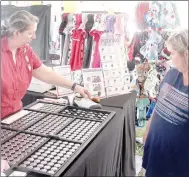  ?? Keith Bryant/The Weekly Vista ?? Bella Vista resident Marti Hudson, left, explains her custom-engraved golf markers to prospectiv­e customer Tina Bauerin.