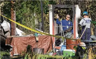  ?? Jason Fochtman / Houston Chronicle ?? Investigat­ors examine the scene of a house fire Friday that killed three children ages 5 to 13 on Johnson Road in the community of Tamina, just east of The Woodlands.