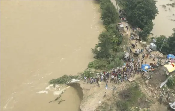  ?? National Disaster Response Force via AP ?? Flood victims wait for rescue and relief, as seen from an Indian Air Force chopper earlier this week over Siddharmhn­agar district, in northern India. Heavy monsoon rains have unleashed landslides and floods that killed hundreds of people in recent days...