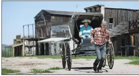  ??  ?? Ethan Kartchner fills in for a horse as he and his mother J.J. give a new buggy a test drive on the main street of the Mescal Movie Set.