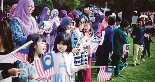  ??  ?? Children waving the Jalur Gemilang at the Merdeka Carnival at Brickendon­bury recently.