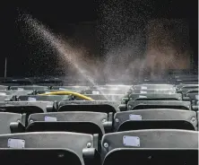  ?? Jessica Christian / The Chronicle ?? Water mists empty stadium seats during an A's workout at the Coliseum. Due to testing delays and prominent players coming down with coronaviru­s, the 60game season looks in question.