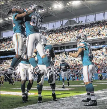  ?? BILL INGRAM / THE PALM BEACH POST ?? Dolphins running back Kenyan Drake (left) and wide receiver Leonte Carroo celebrate Carroo’s touchdown against the 49ers on Sunday at Hard Rock Stadium. It was his first touchdown in the NFL.