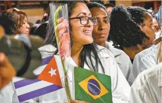  ?? AFP PHOTO - ACN (CUBAN NEWS AGENCY) / MARCELINO VAZQUEZ ?? Médicos desembarca­m no aeroporto, em Havana, de jaleco e carregando bandeiras dos dois países