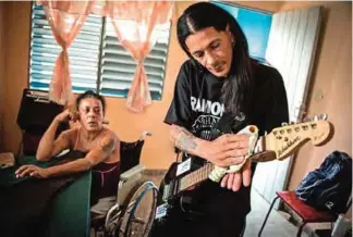  ?? — AFP photos ?? AIDS affected Yohandra (left) listens to also AIDS patient Gerson playing guitar without strings.