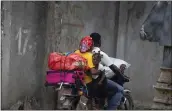  ?? ODELYN JOSEPH — THE ASSOCIATED PRESS ?? Residents travel on a motorbike as they flee their home to avoid clashes between armed gangs, in the Croix-desMission neighborho­od of Port-au-Prince, Haiti, Thursday. Experts say the scale and duration of gang clashes, the power they are wielding and the amount of territory they control has reached levels not seen before.