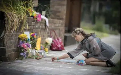  ?? ELIZABETH FLORES, TNS ?? Megan O’Leary of St. Paul, Minn. leaves a message on the sidewalk on Monday, near the scene where a Minneapoli­s police officer shot and killed Justine Damond, in Minneapoli­s, Minn.