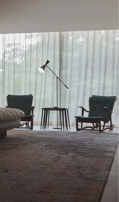  ??  ?? The master bedroom is also outfitted in basalt flooring and walnut walls, with a rug by Jan Kath bringing a soft touch. A coffee table by Vladimir Kagan is paired with a Flexform sofa