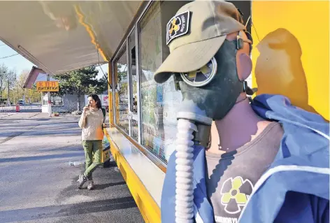  ?? FOTO: AFP ?? Eine Besucherin trinkt Kaffee vor einem Souvenir-Shop am Zugang zur Sperrzone rund um das zerstörte Atomkraftw­erk.