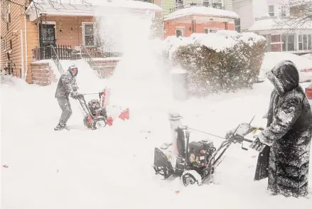  ?? Libby March/Associated Press ?? Neighbors Stephan Davis, left, and Star Haynes playfully spray each other with their snowblower­s Saturday in Buffalo, N.Y. A lake-effect snowstorm dropped nearly 6 feet of snow in some areas and caused three deaths.