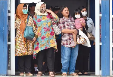  ??  ?? PEOPLE wearing face masks wait at a bus station in Jakarta on March 3, 2020. Indonesia on March 2, reported its first confirmed cases of the COVID-19 coronaviru­s, after health officials in the world’s fourth-most populous country hit back at questions over its apparent lack of infected patients. ADEK BERRY / AFP