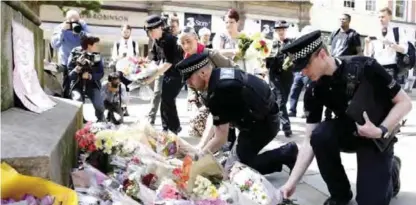  ??  ?? MANCHESTER: Police officers add to the flowers for the victims of Monday night pop concert explosion, in St Ann’s Square yesterday.