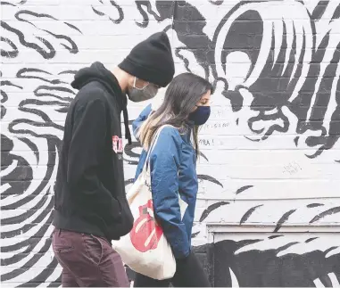  ?? GRAHAM HUGHES / THE CANADIAN PRESS ?? Two Montrealer­s walk past a mural on Sunday. Ontario and Quebec — the two provinces that account for the
bulk of Canada's COVID-19 case count — reported 1,487 and 1,218 new infections, respective­ly, on Monday.