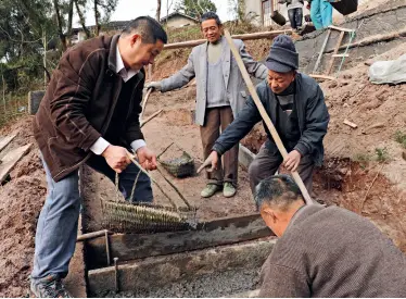  ??  ?? Jiang Yijia (right) repairing a road with villagers in January 2011.