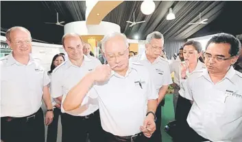  ??  ?? Najib (centre) takes a whiff of perfume after the ground-breaking ceremony for the complex. Also seen are Shamsul (third right) and Brudermull­er (second left). — Bernama photo