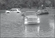  ?? NWA Democrat-Gazette/BEN GOFF @NWABENGOFF ?? Bryce Myers of Rogers uses his Dodge pickup to pull two motorists out of high water Saturday after they became stuck in high water on South 52nd Street in Rogers.