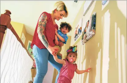  ?? Christian Abraham / Hearst Connecticu­t Media ?? Katie Coelho with her children, Penelope, 22 months, on the stairs, and Braedyn, 3, in his mother’s arms, Thursday at her Southbury home. Thursday was the one-year anniversar­y of her husband Jonathan Coelho’s death from COVID-19.