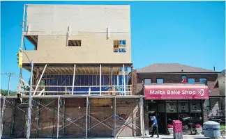  ??  ?? A new condominiu­m is being built beside the Malta Bake Shop in Toronto’s Junction area but bakery owners Charlie, left, and Antoinette Buttigieg refused to sell their property to the developer and continue to work in the kitchen as they have for 40 years, calling the shop a “living room” and their customers “family.”