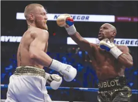  ?? The Associated Press ?? Floyd Mayweather Jr. connects with a punch on Conor McGregor during their boxing match last Saturday in Las Vegas.