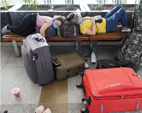  ?? — Bloomberg photos by T. Narayan. ?? Travelers rest on benches at Delhi Airport.