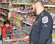  ?? / Doug Walker ?? Little Veer Patel, 5 puts an item into his basket being pushed by Floyd County officer Michael Poster during the Shop With a Cop event Saturday at Walmart on U.S. 411.