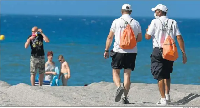  ?? PHOTOGRAPH­ERSSPORTS ?? Dos personas contratada­s de modo urgente por la Junta de Andalucía para reforzar el cumplimien­to de las normas el pasado verano, en una playa de Granada.