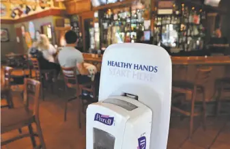  ??  ?? A hand sanitizing station inside the entrance to Downtown Joe's, which is among the restaurant­s in Napa that have reopened with new state safety requiremen­ts in place.
Customers Brett and Julia Estrada enjoy a meal at newly reopened Downtown Joe’s. Businesses can’t reopen in counties that haven’t met the state’s strict guidelines, including declining numbers of COVID19 cases.