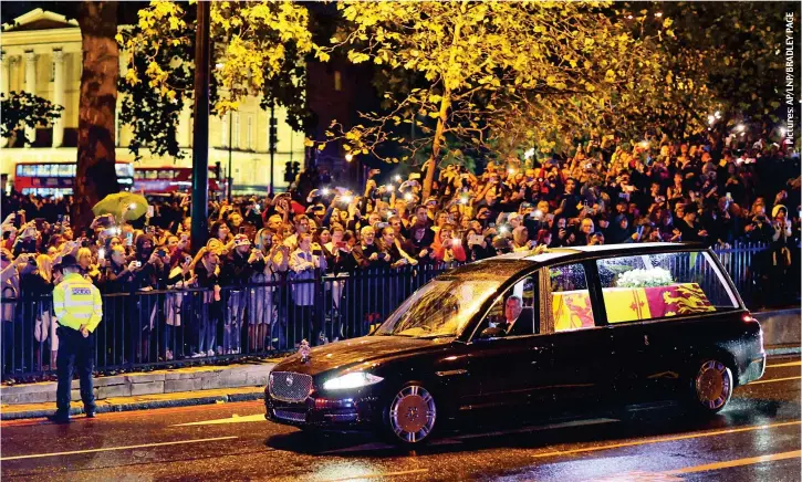  ?? ?? Packed pavements: A policeman bows his head as the Queen’s hearse passes the thousands of people crowding the streets around Hyde Park Corner last night