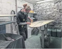  ?? ?? Matthew Lawrence tapes a custom surfboard in the studio of the designer Julian Matthews in the seaside resort of Woolacombe.