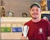  ?? CONTRIBUTE­D ?? Justin Olive, GM at Common Grounds Coffee Bar, holds paper straws the store will start using Monday.