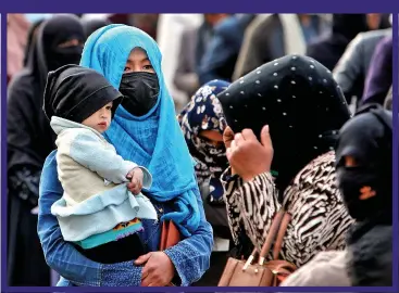  ?? ?? DESPERATE NEED: Cradling her child, a woman queues for a charity aid package in Kabul