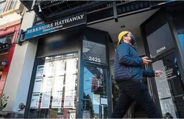  ??  ?? Still optimistic: A pedestrian walks past a Berkshire Hathaway Homeservic­es real estate office in California. Buffet retained his trademark optimism for Berkshire, buying back a record Us$24.7bil of its stock in 2020 in a sign he considers it undervalue­d. — Bloomberg