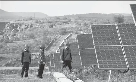  ?? SONG WEIXING / FOR CHINA DAILY ?? State Grid employees inspect photovolta­ic panels in Chuzhou, Anhui province.