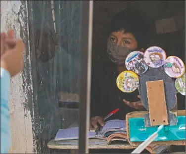  ??  ?? Eleven-year-old Oscar Rojas listens to Ixcoy outside Oscar’s home. The pandemic has really altered Oscar’s routine, “because now I’m not receiving normal classes,” he said