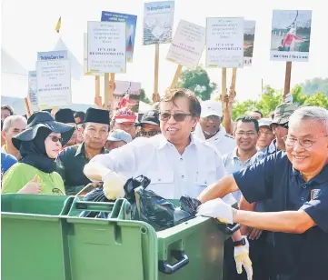  ??  ?? Abang Johari and Talib (right) throw rubbish into the trash bin as a gimmick at the launching ceremony.