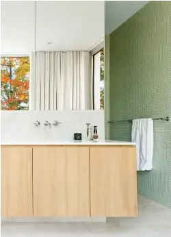  ??  ?? Au centre de la pièce, le meuble-lavabo qui combine bois clair et surfaces marbrées sépare le coin baignoire du coin douche. Coup de coeur pour les miroirs et la mosaïque de céramique vert tendre qui invitent la nature à l'intérieur.