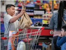  ?? JIM WEBER/THE NEW MEXICAN ?? Daniel Chacon, 9, claims the paper bag full of groceries from the conveyor belt at the south-side El Paisano Supermarke­t while his mother finishes up paying Monday. Sen. Jeff Steinborn is proposing a state ban on single-use plastic bags similar to Santa Fe’s.