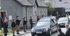  ??  ?? Members of Oban Pipe Band pay their respects to Angus MacLennan as his cortege drives along Shore Street.