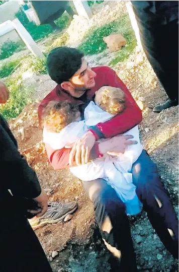  ??  ?? Abdulhamid al-Youssef gives his nine-month-old twins one last hug before burying the infants who, along with his wife Dalal and 16 other members of his family, were killed by a chemical attack on the town of Khan Sheikhoun in Idlib, northern Syria