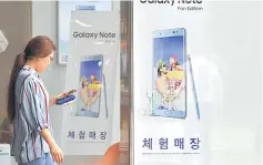  ??  ?? A woman walks past advertisin­g showing the Samsung Galaxy Note Fan Edition smartphone at a Samsung mobile store in Seoul. Samsung will be confronted by tougher challenges in the future as Chinese rivals take aim at its semiconduc­tor business and...