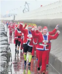  ?? Pictures: Adrian White ?? Running Santas in the windswept, rain-soaked 5k race in Aberavon.