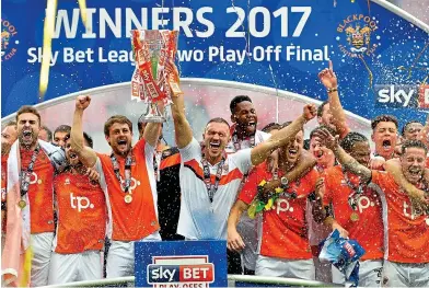  ?? GETTY IMAGES ?? Blackpool rocks: Andy Taylor (left) and Tom Aldred lift the trophy at Wembley