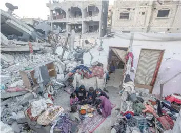  ?? — AFP ?? A Palestinia­n family break their fast amidst the rubble of their home, during the holy month of Ramadhan in Rafah.